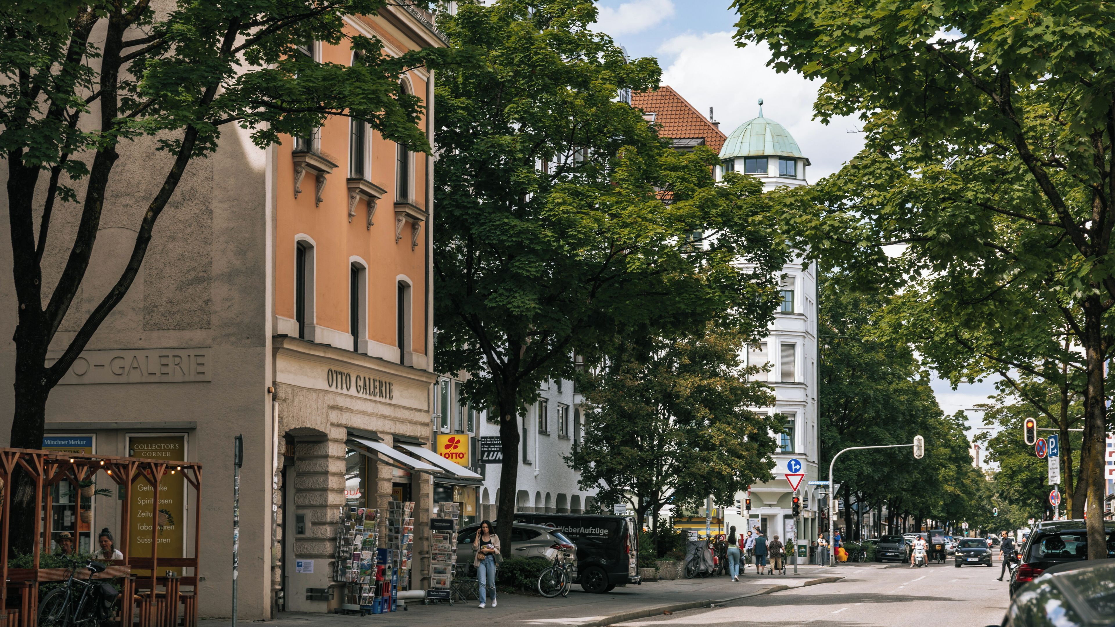 A street lined with trees, a building with a dome, and a sign for Otto Galerie.