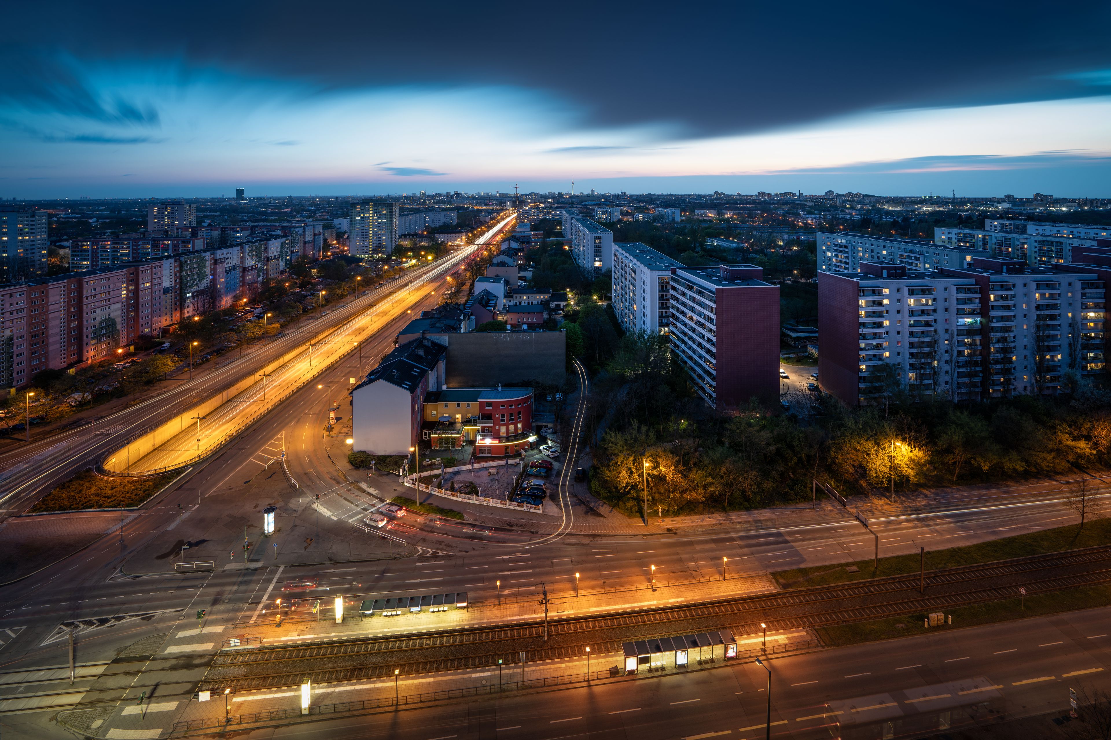 Une vue d’une ville au crépuscule, avec des routes et des bâtiments illuminés.