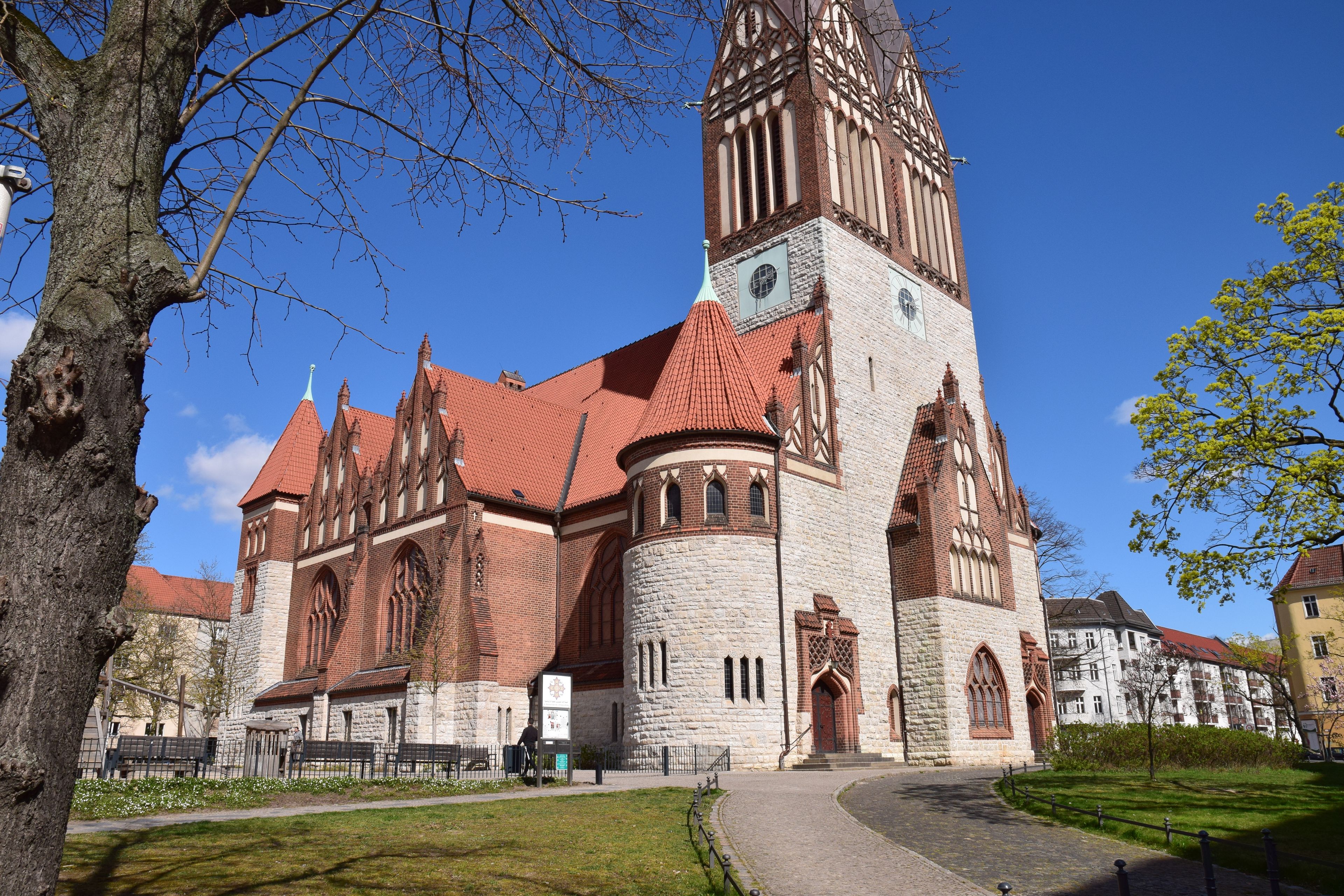 Une église historique dotée d’un clocher imposant et d’un toit recouvert de tuiles rouges.