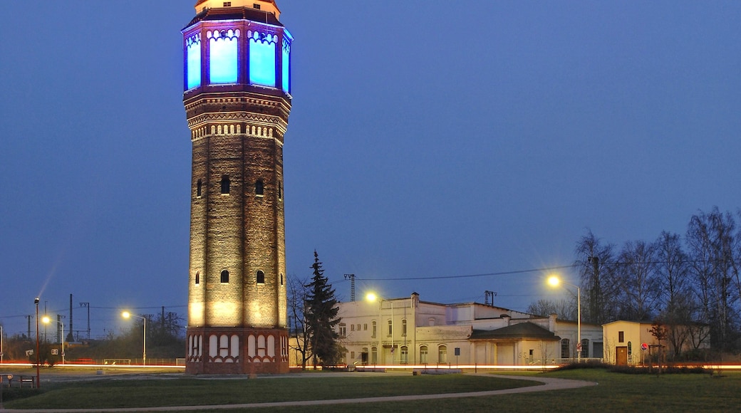 A tower with a red roof and blue lights at dusk.