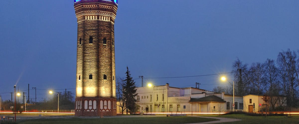 A tower with a red roof and blue lights at dusk.