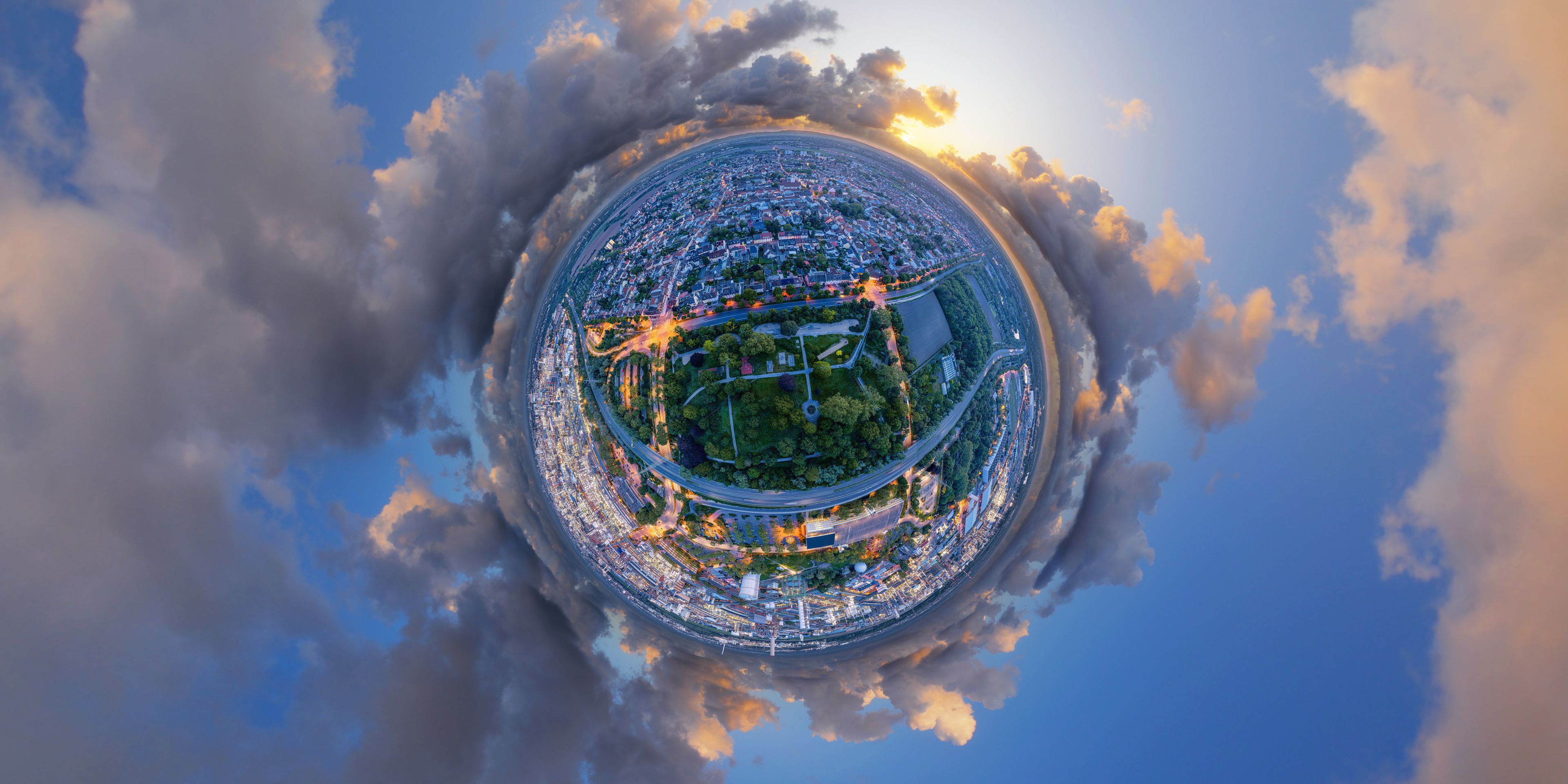Een panoramisch stadsgezicht met een centraal park, omringd door straten en gebouwen.