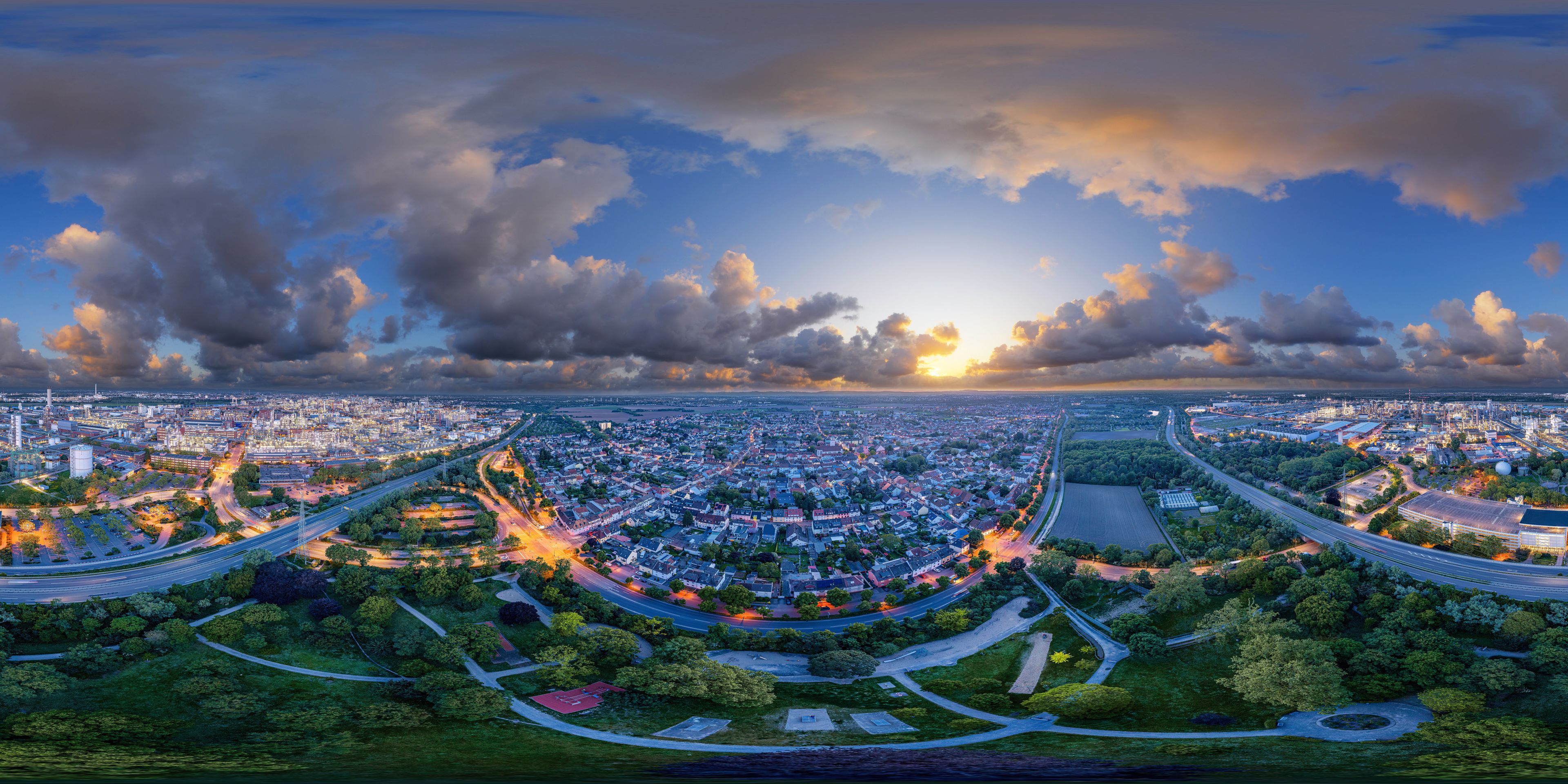 Een panoramisch stadsbeeld met een opvallende rotonde, een dichtbebouwd stedelijk gebied en een zonsonderganglucht.