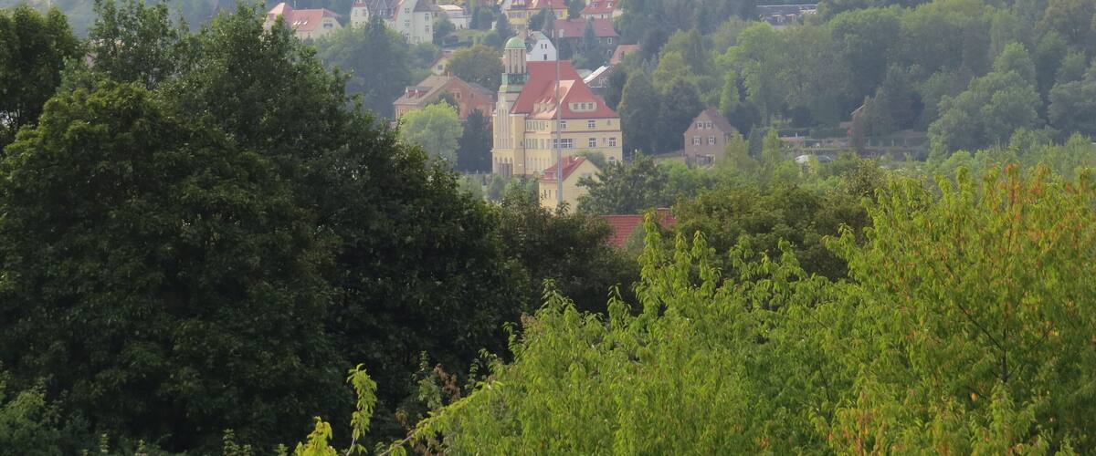 A town nestled in a valley with red-roofed houses and a prominent church.