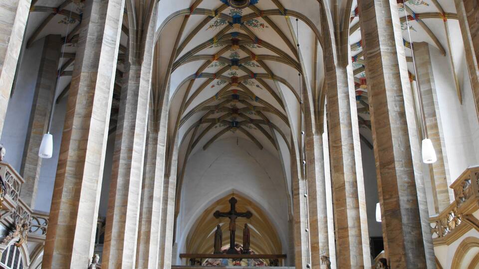 A cathedral interior with high vaulted ceilings, stained glass windows, and ornate statues.