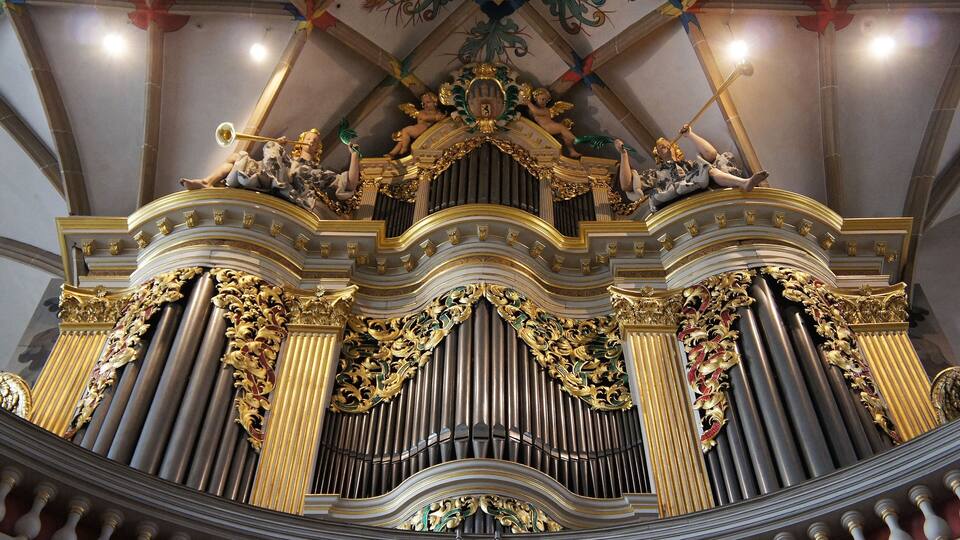 An ornate organ with gold accents and statues.