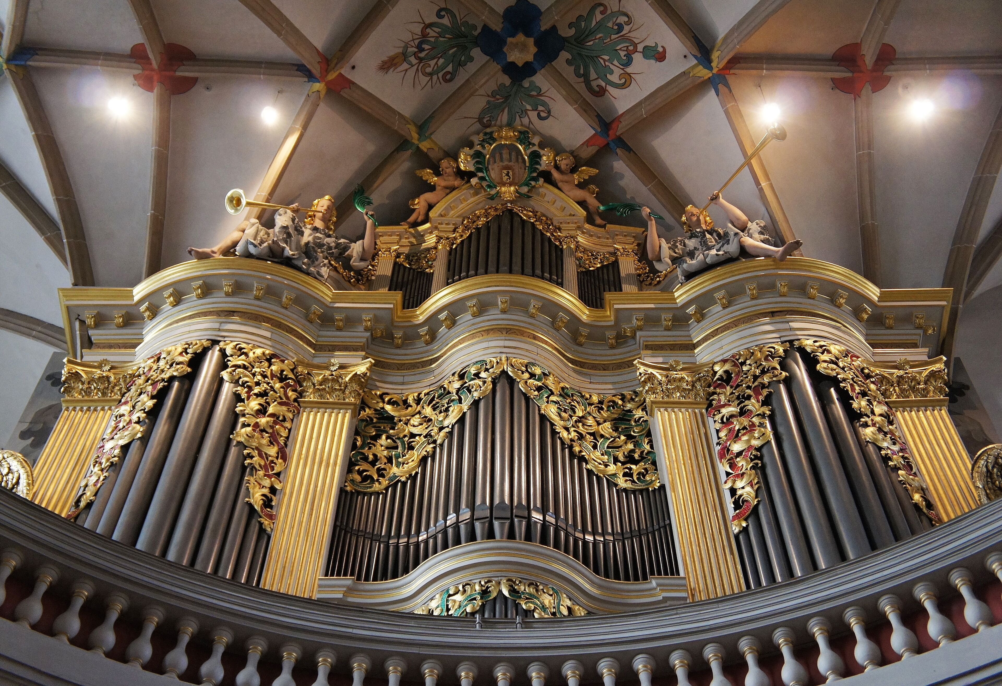 An ornate organ with gold accents and statues.