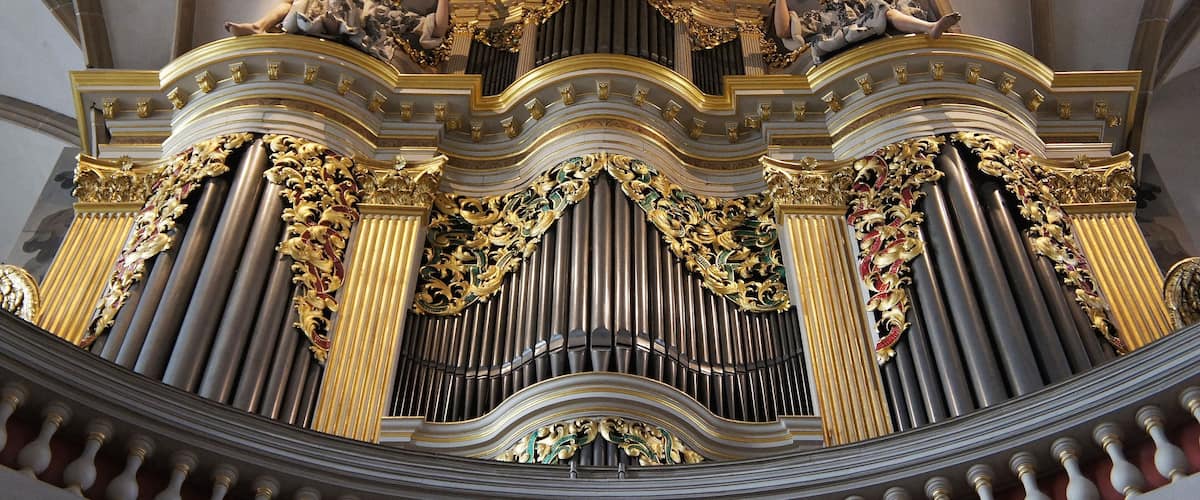 An ornate organ with gold accents and statues.
