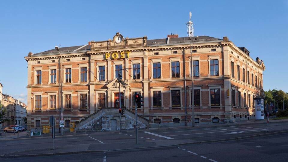 A historic building with a prominent 'POST' sign, large windows, and a clock tower.