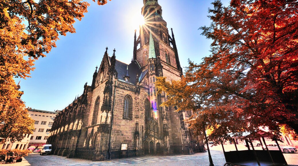 A historic church with a tall spire, surrounded by autumn trees.