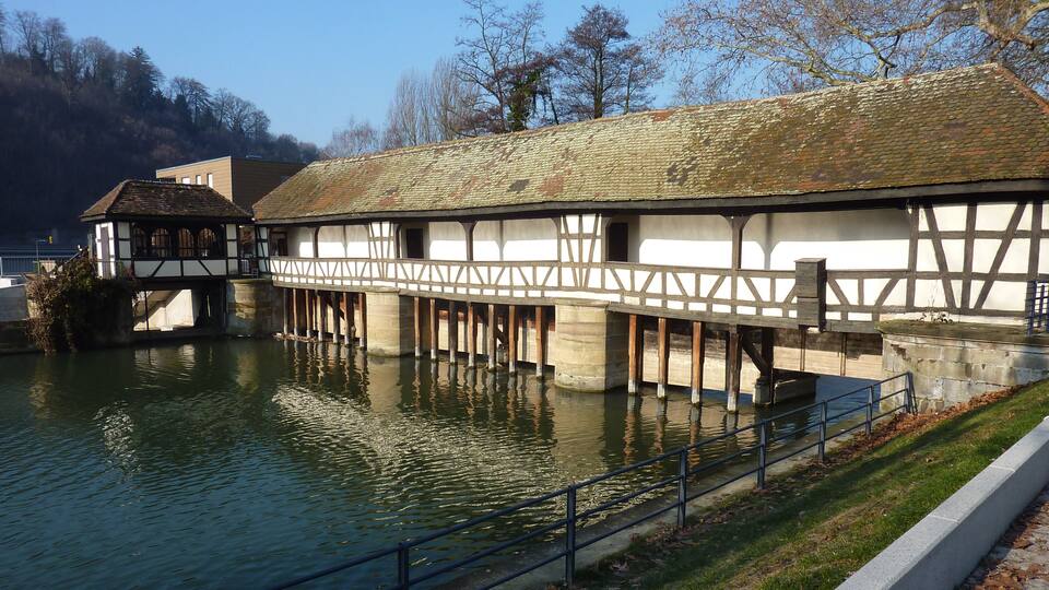 A historic building with a timber-framed structure over a body of water.