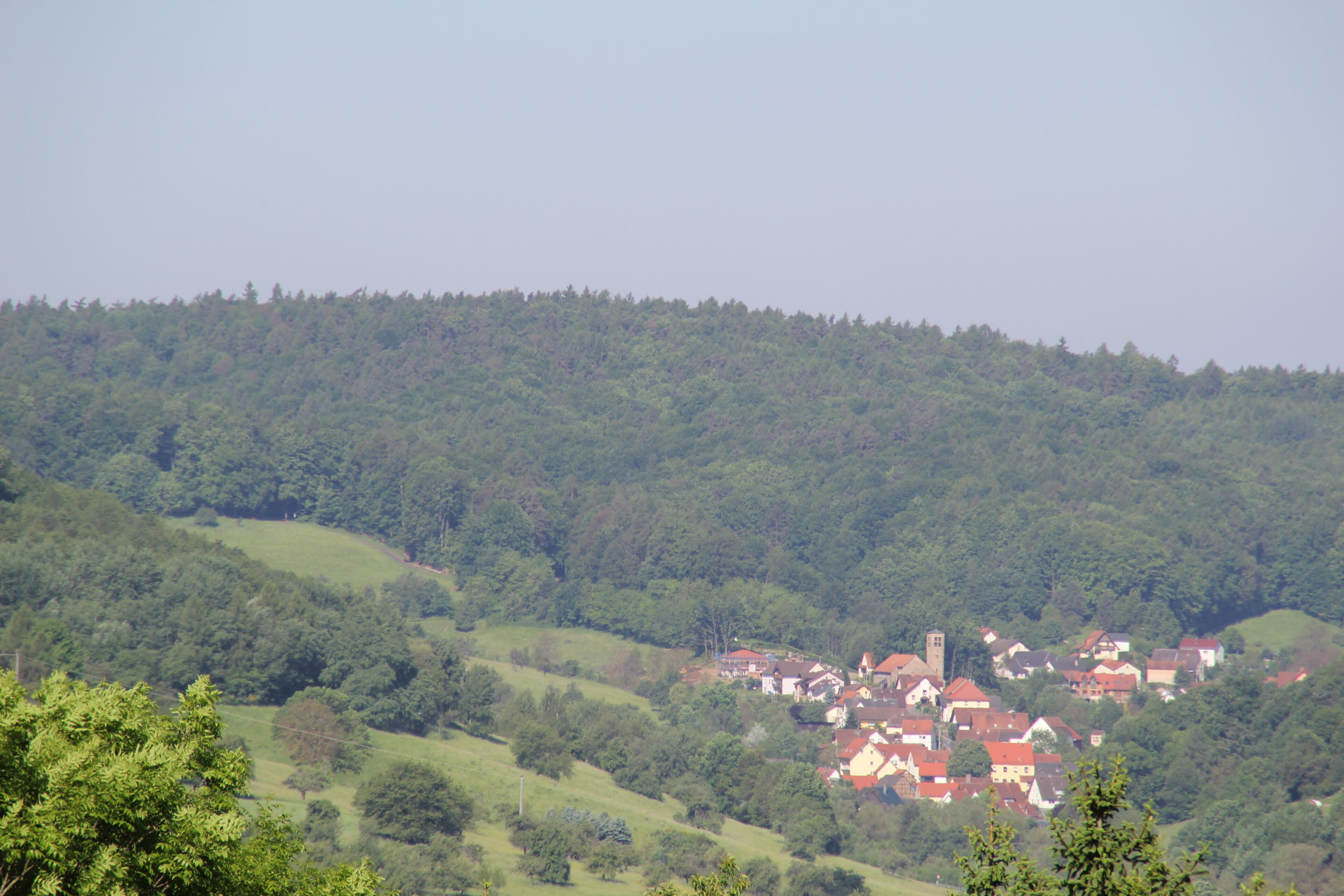 A village nestled in a valley surrounded by forested hills.