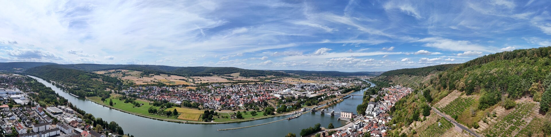 Una vista panorámica de un río que atraviesa un pueblo rodeado de colinas y campos.