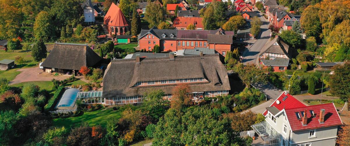 Ein Dorf mit traditionellen Häusern, einer Kirche und Windkraftanlagen in der Ferne.