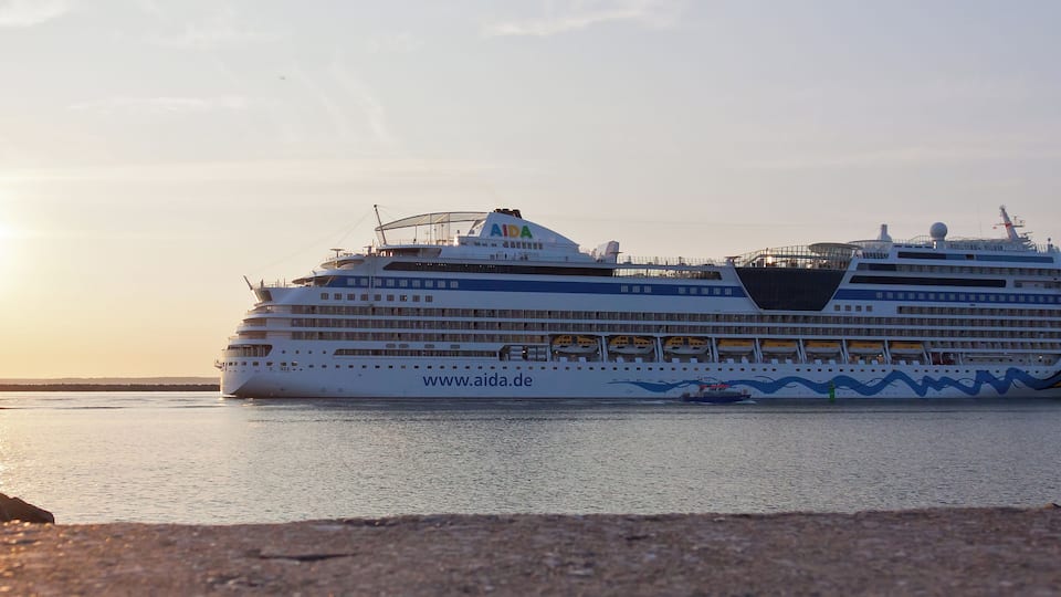 The AIDAblu sailing through the port entrance of Warnemünde on the 04th of Juli 2010. The marina of Hohe Düne is discernible in the right background of the photograph.