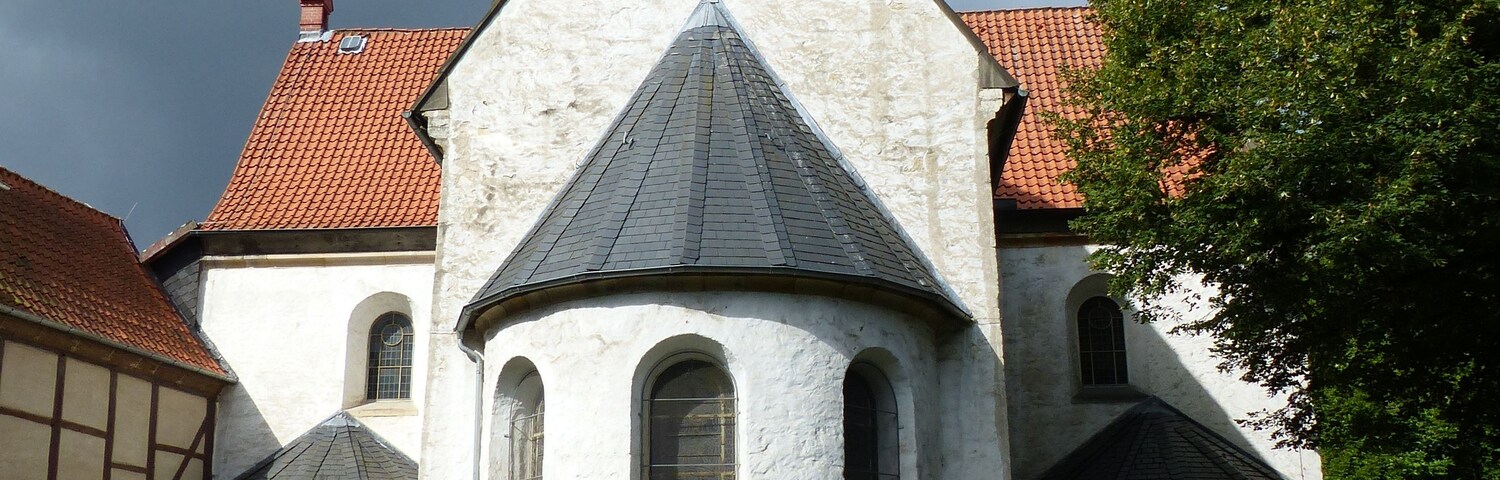 Una iglesia blanca con techo empinado y ventanas arqueadas.
