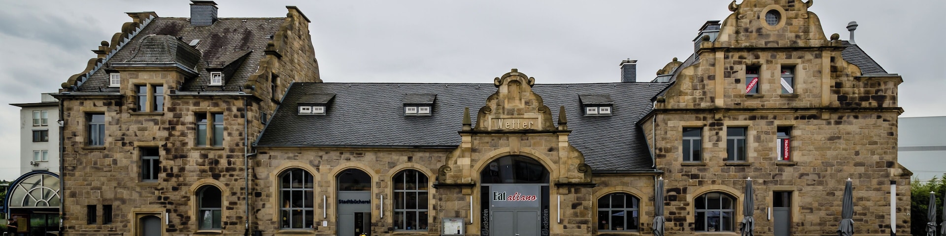 A historic stone building with arched windows and a sign that reads "Stadtbücherei".