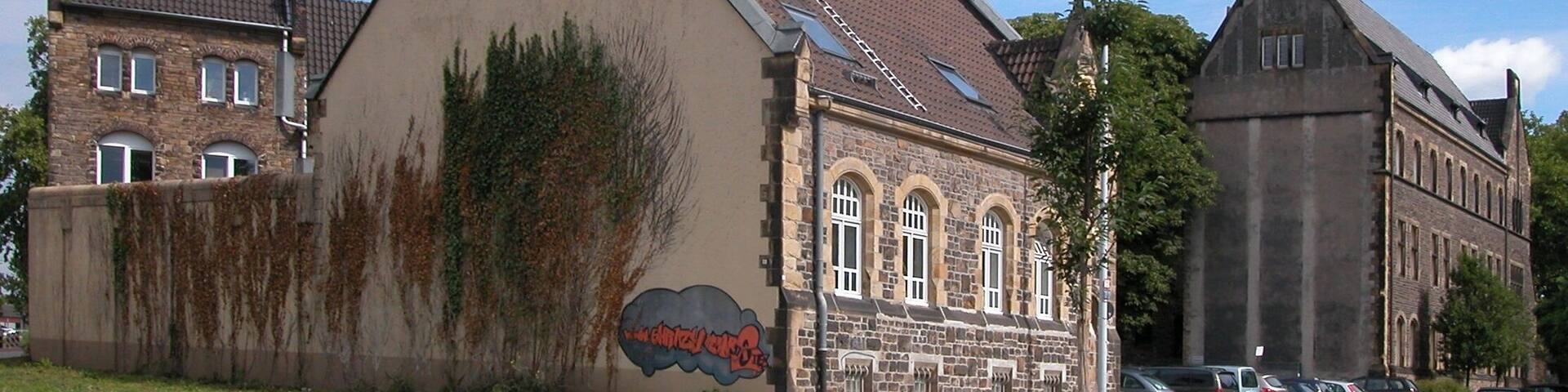 A historic building with a stone facade, a sloped roof, and a mural on the side.