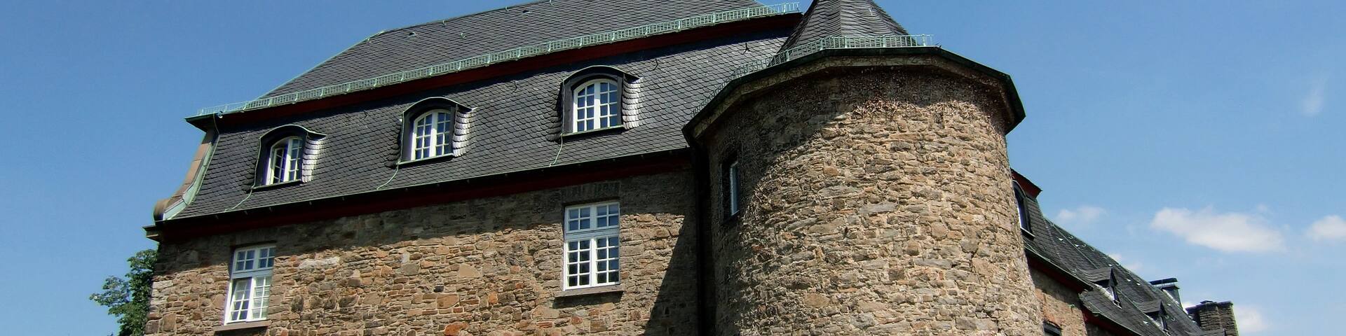 A historic stone building with a prominent tower and multiple windows.