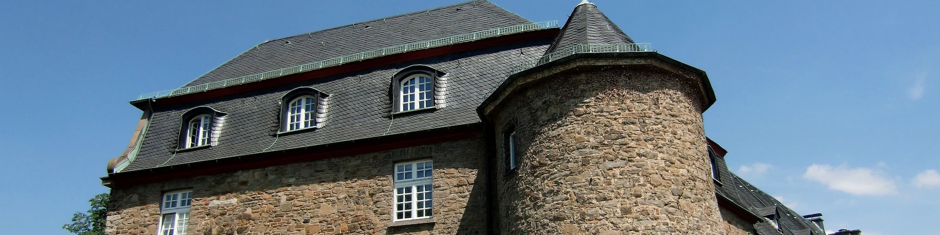 A historic stone building with a prominent tower and multiple windows.