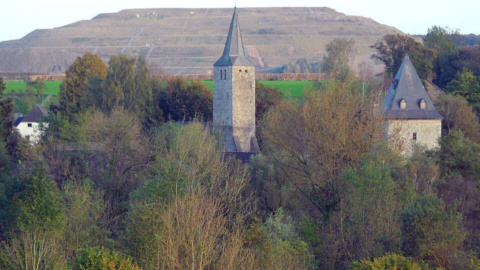 Wuppertal-Schöller: protestant parish church (centre), and defence tower of Gut Schöller (right); in background premises for limestone mining; October 2014