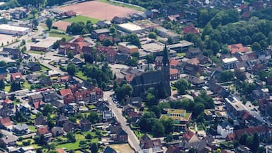 Une vue aérienne d’une ville avec une église imposante, des maisons d’habitation et un terrain de sport.