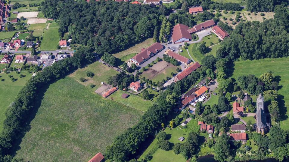 An aerial view of a village with houses, a church, and a river.