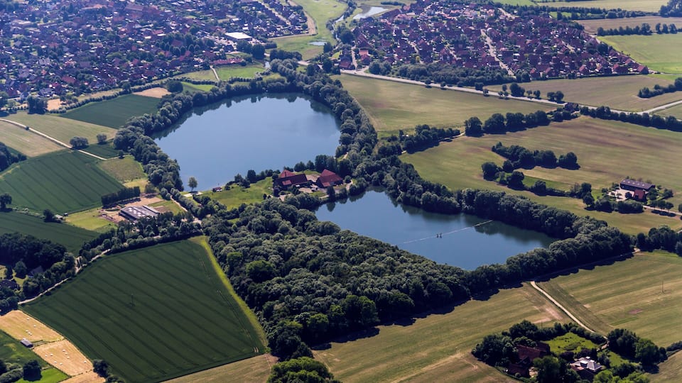 An aerial view of a heart-shaped lake surrounded by fields and houses.