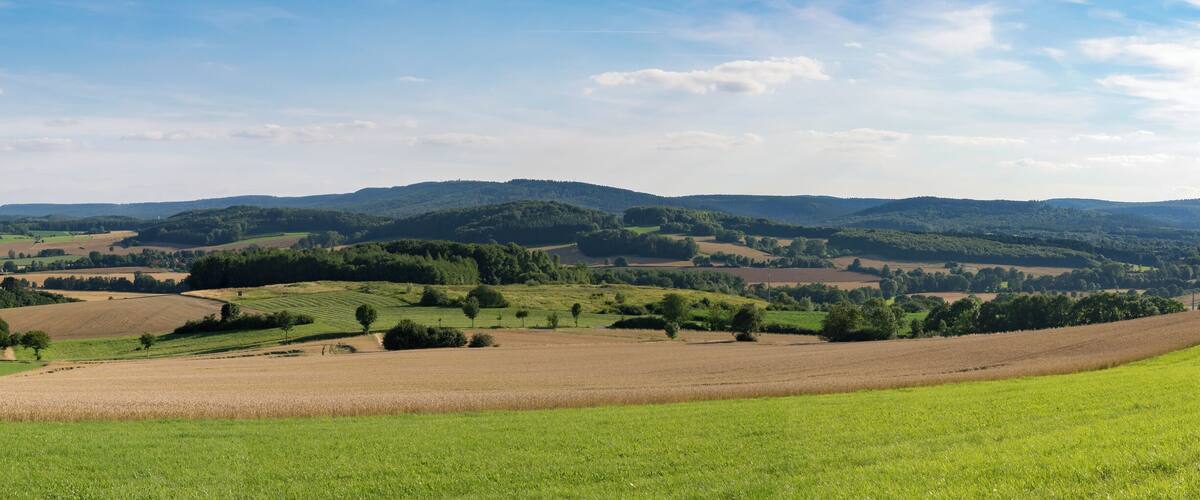 Rolling hills, fields, and distant mountains under a clear sky.