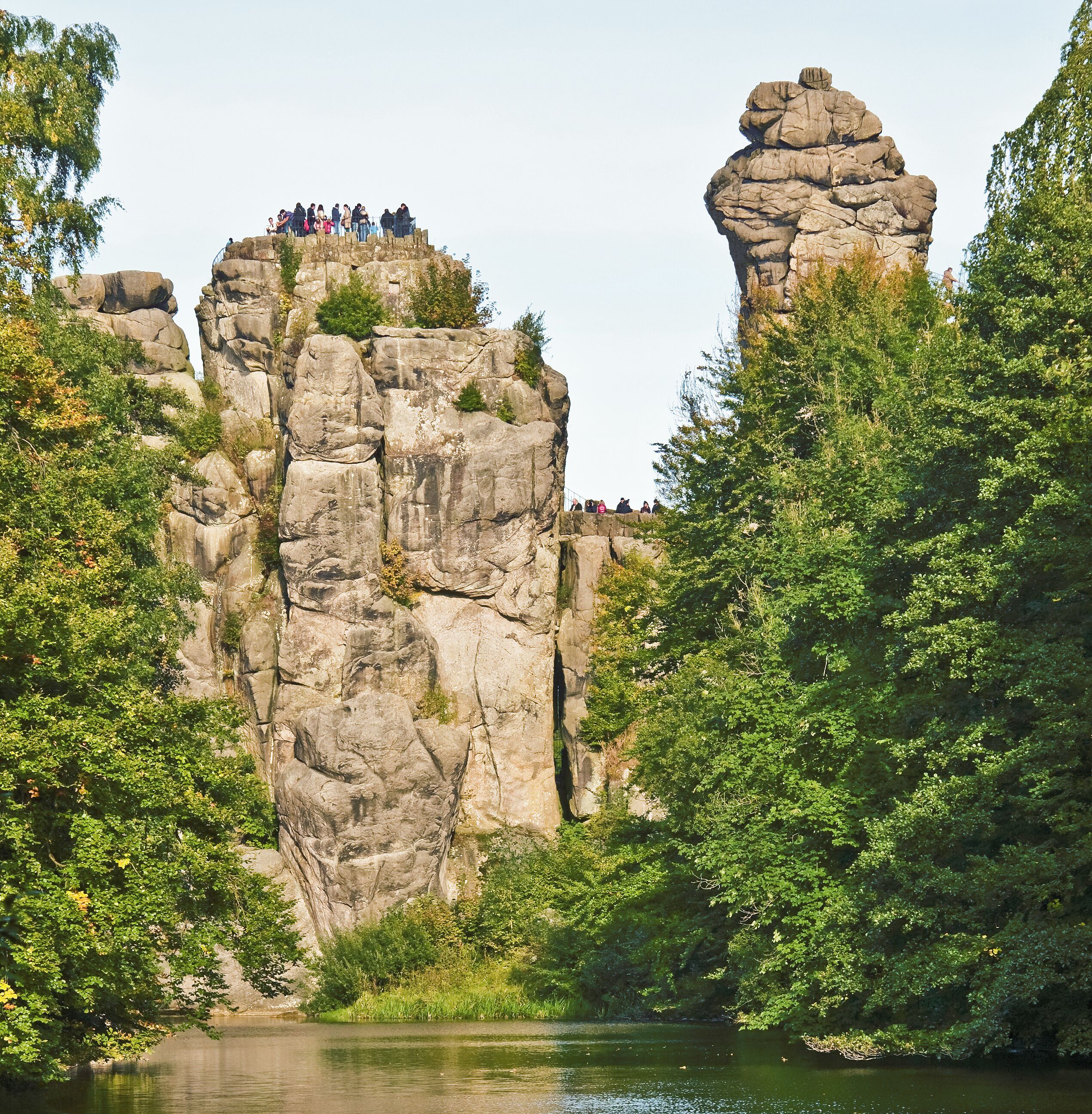 A rocky cliff with a group of people standing on top.
