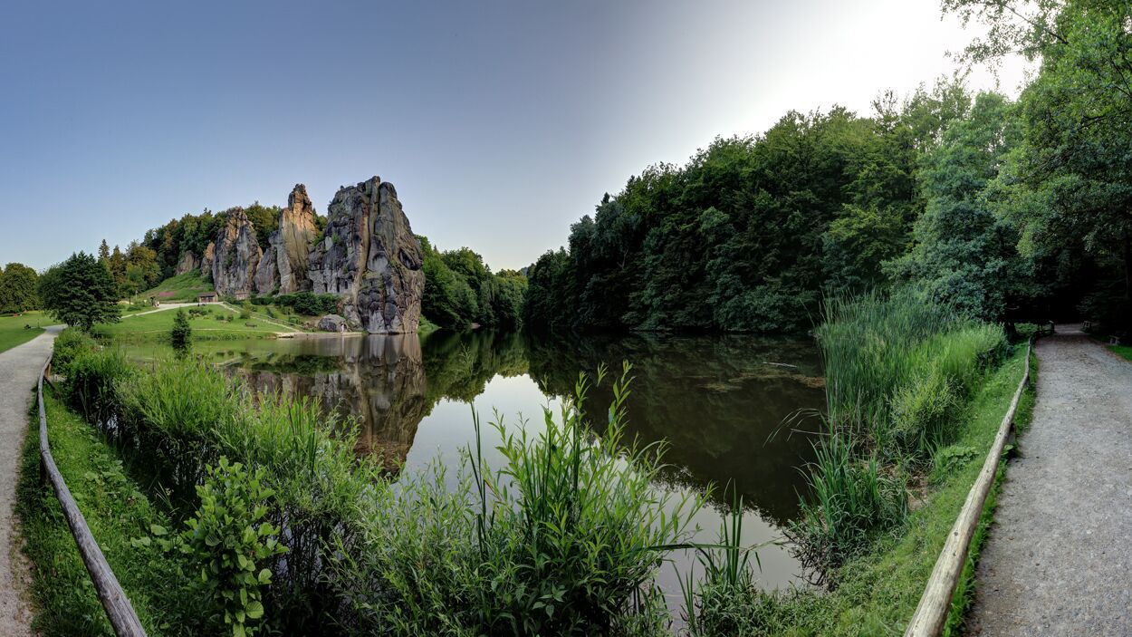 A serene landscape with a rocky outcrop, a calm pond, and lush greenery.