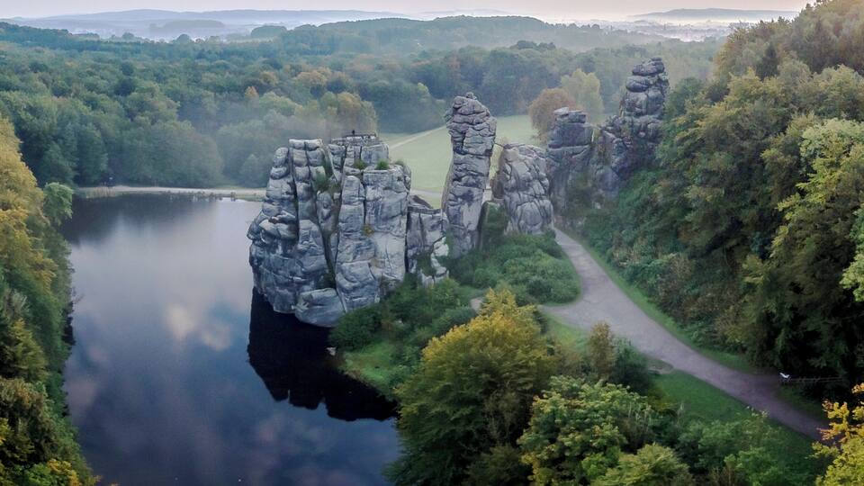 A scenic landscape with a lake, a winding path, and rock formations.