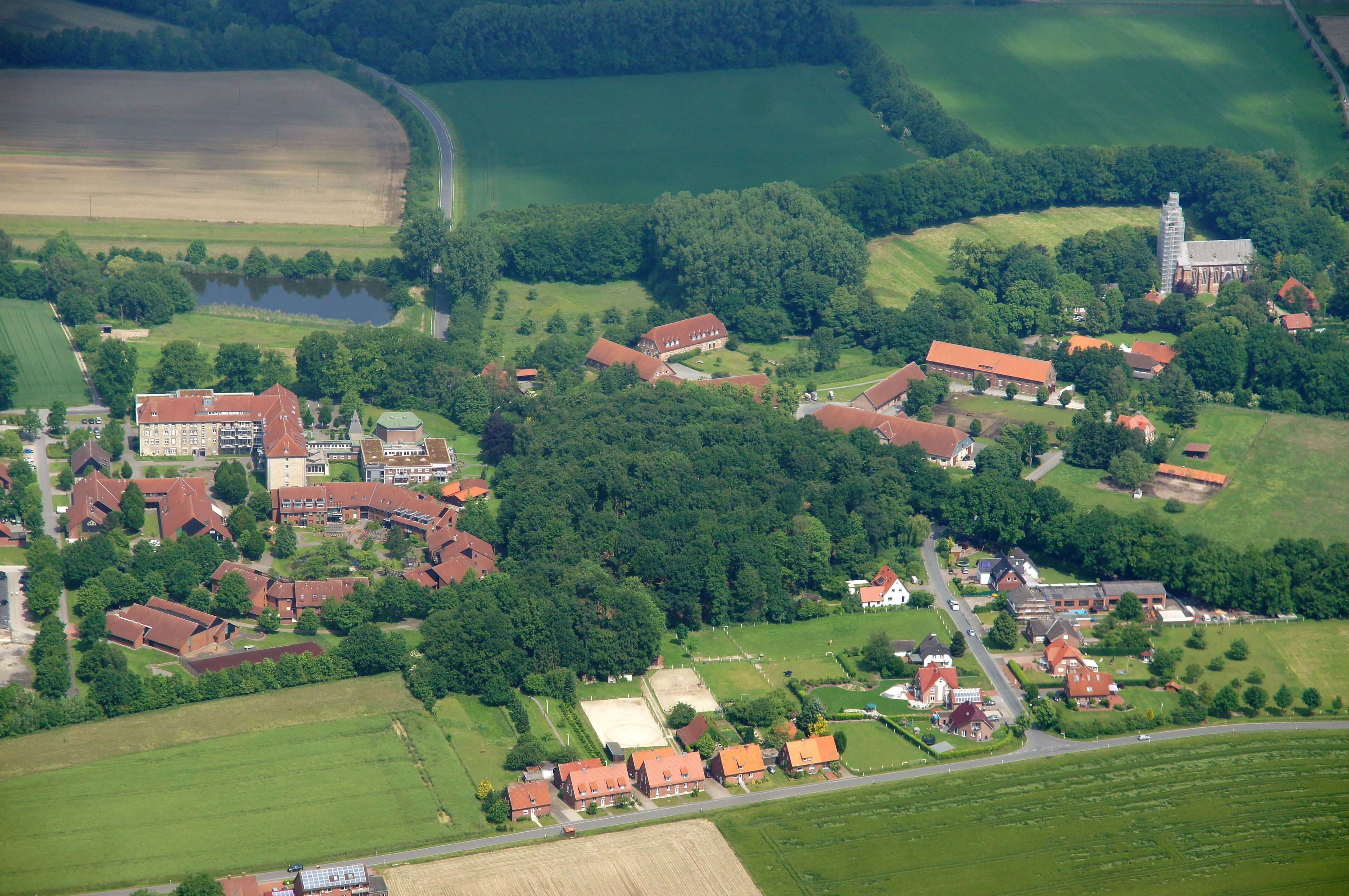 An aerial view of a rural village with houses, a church, and surrounding fields.