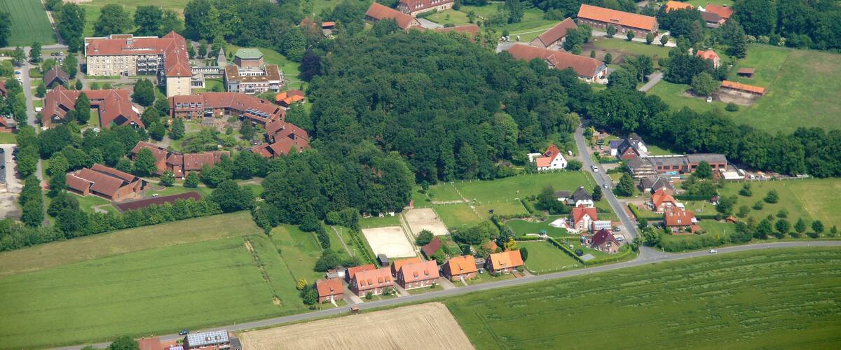 An aerial view of a rural village with houses, a church, and surrounding fields.