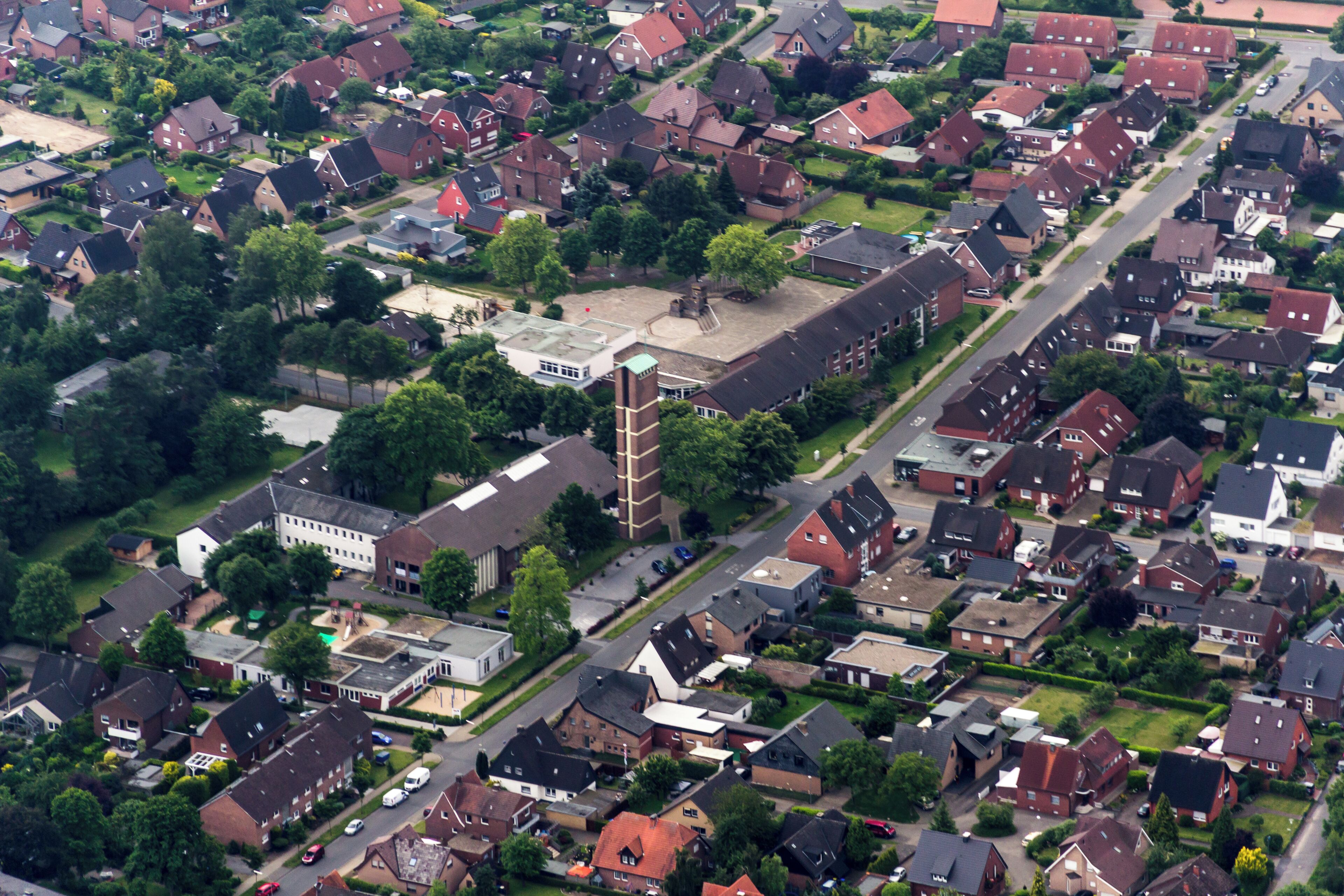 An aerial view of a residential neighborhood with houses, a church, and a central square.