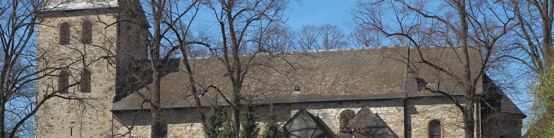 A historic stone church with a tall bell tower and arched windows.