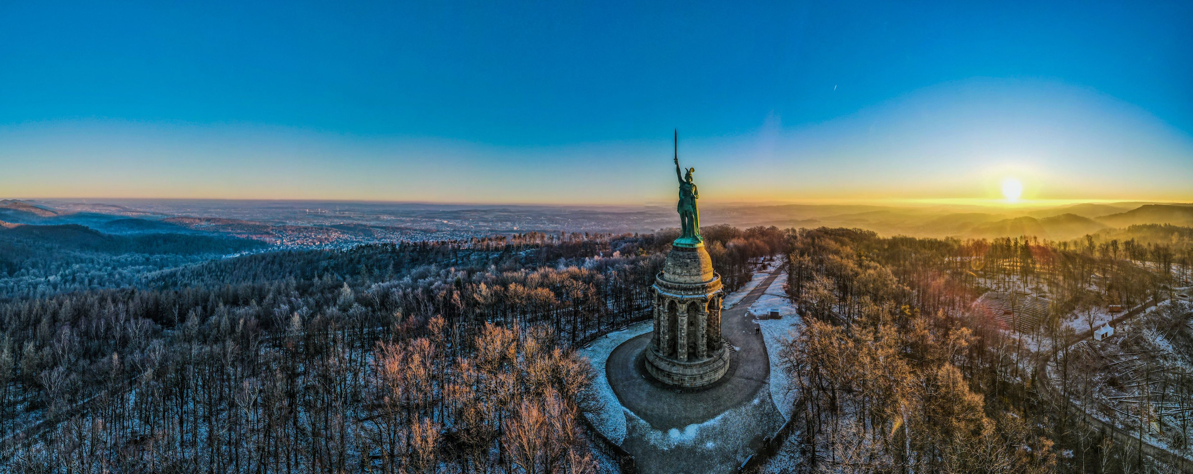 A statue in a snowy landscape with a clear sky.