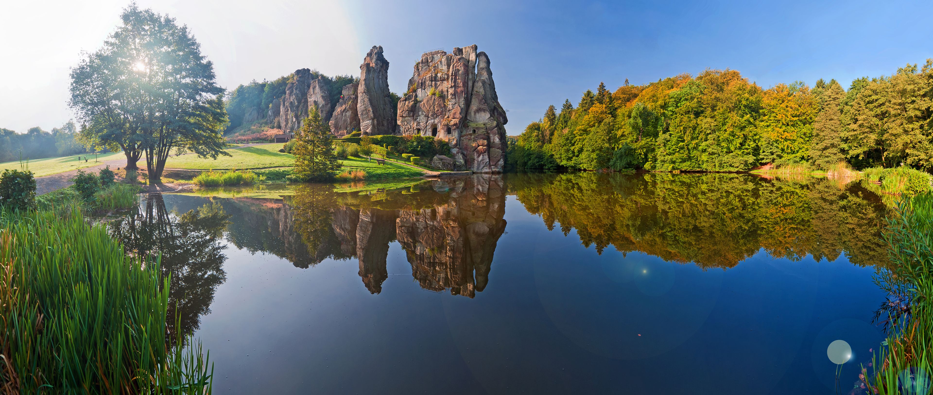 A calm lake reflecting rock formations and trees.