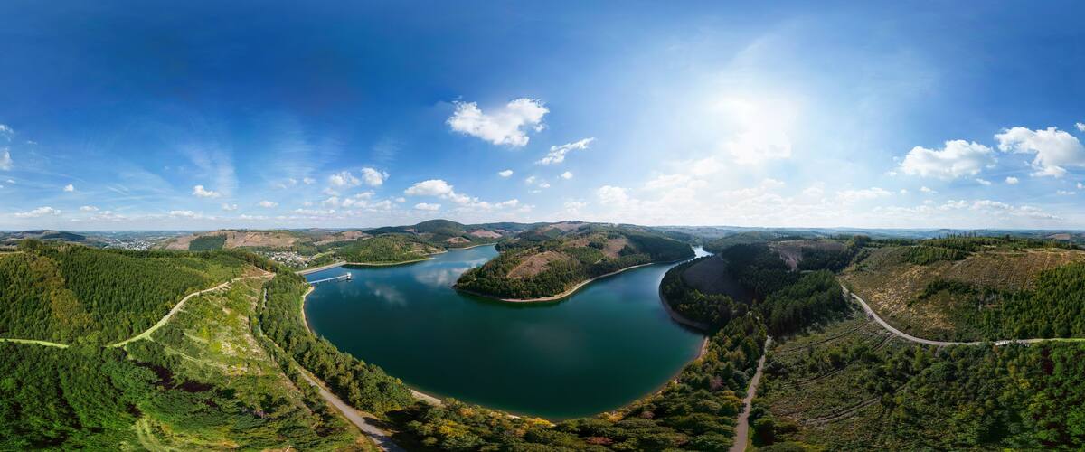 A panoramic view of a lake surrounded by forested hills.