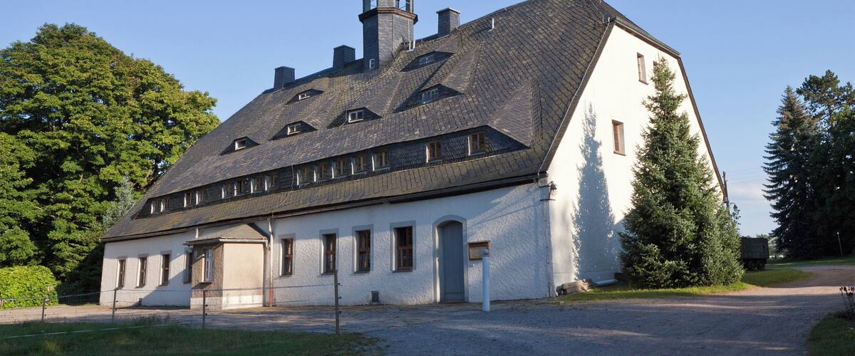 A large white building with a steeply pitched roof and a tower.