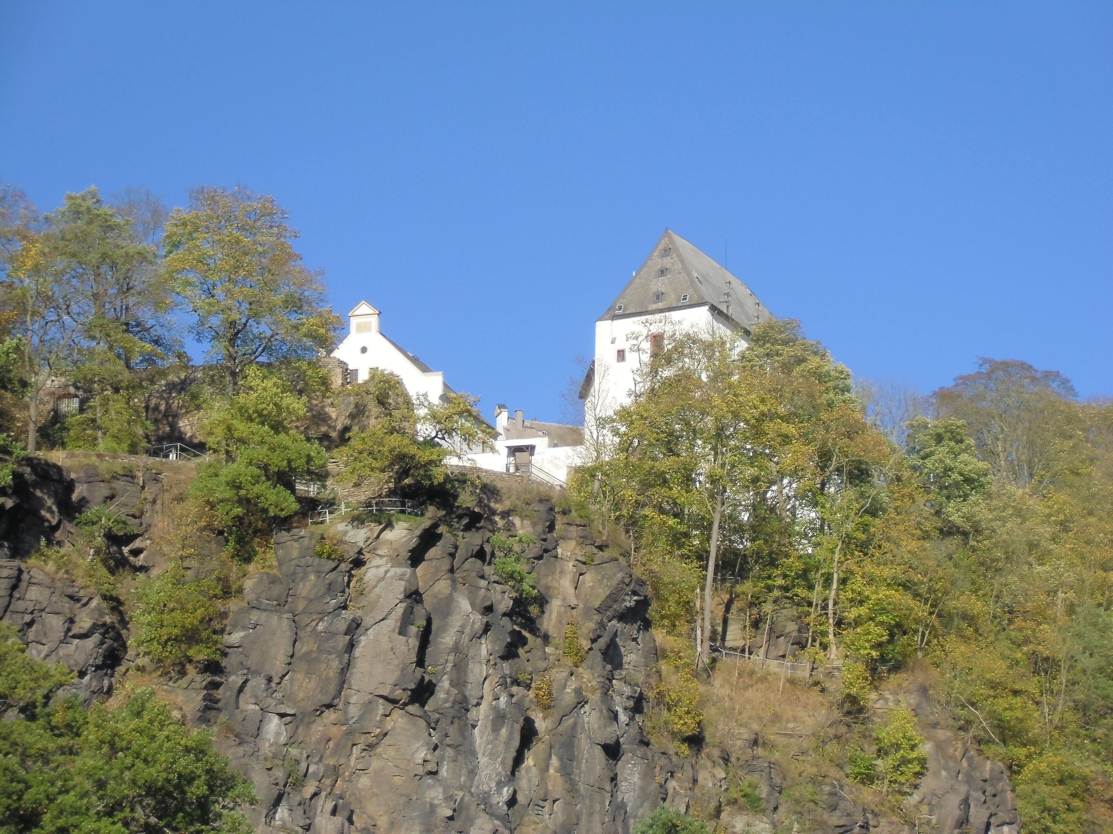 A castle on a rocky hill with trees.