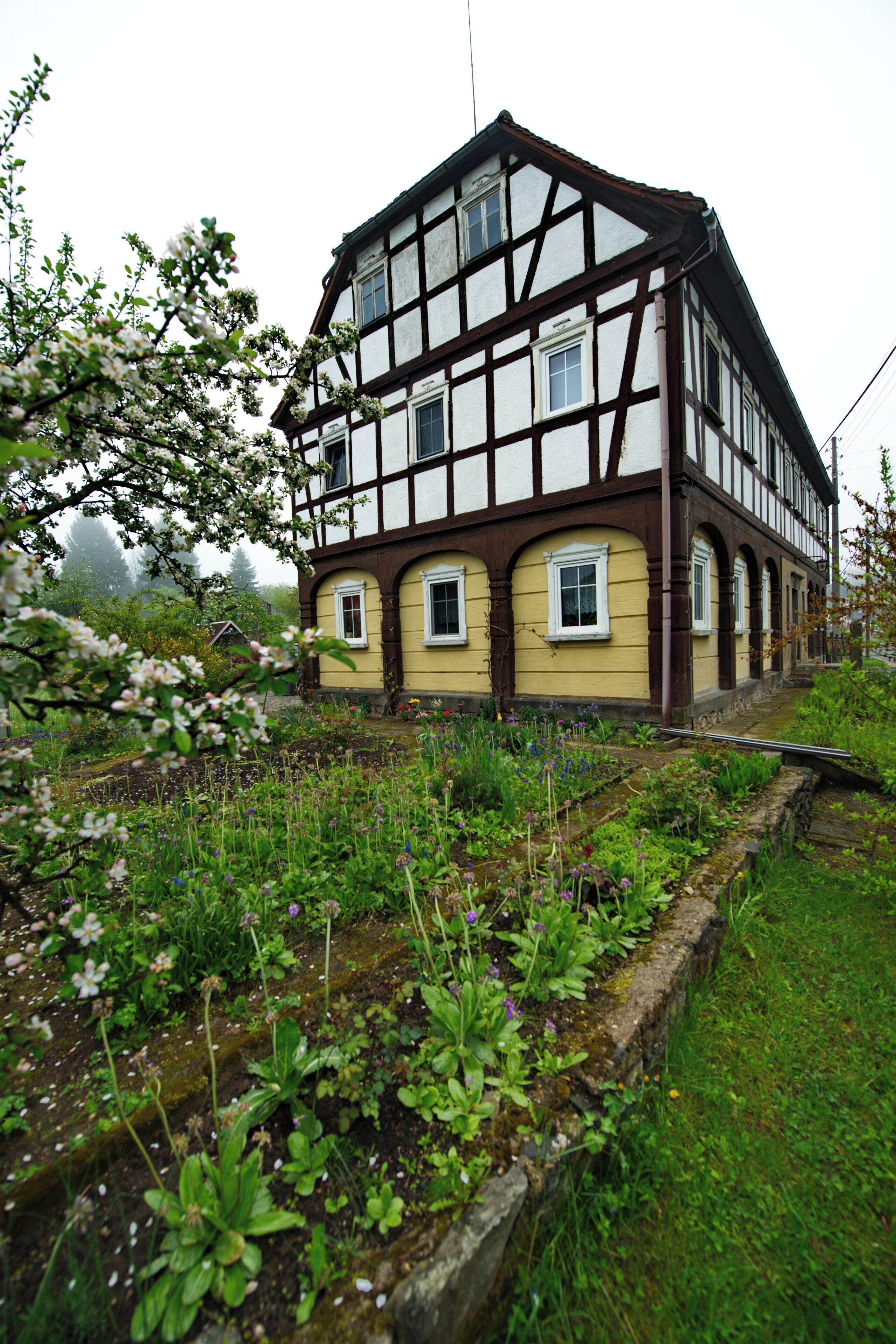 A traditional half-timbered house with a garden in front.
