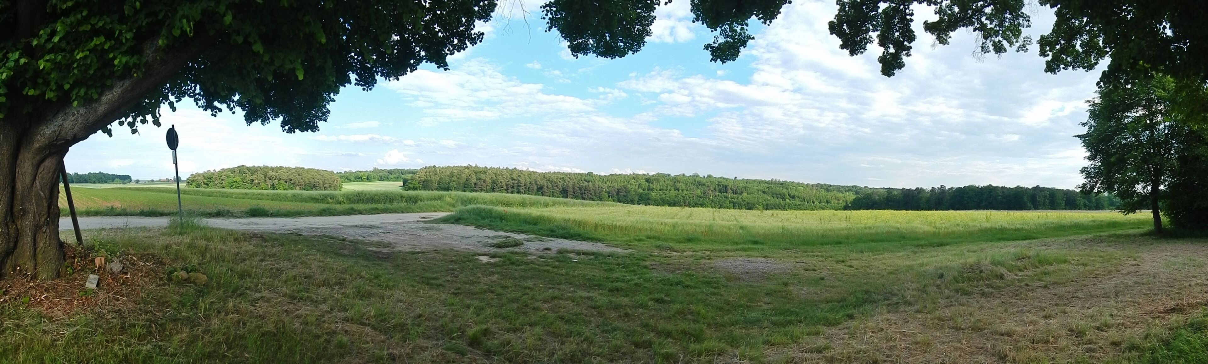 A rural landscape with a river, fields, and a forested hill.