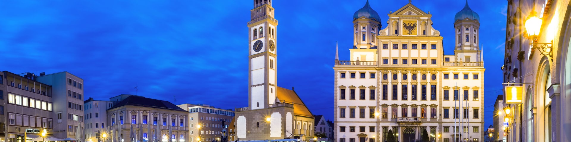 Ein historischer Platz mit einem markanten Glockenturm und einem prunkvollen Gebäude mit Kuppeln.