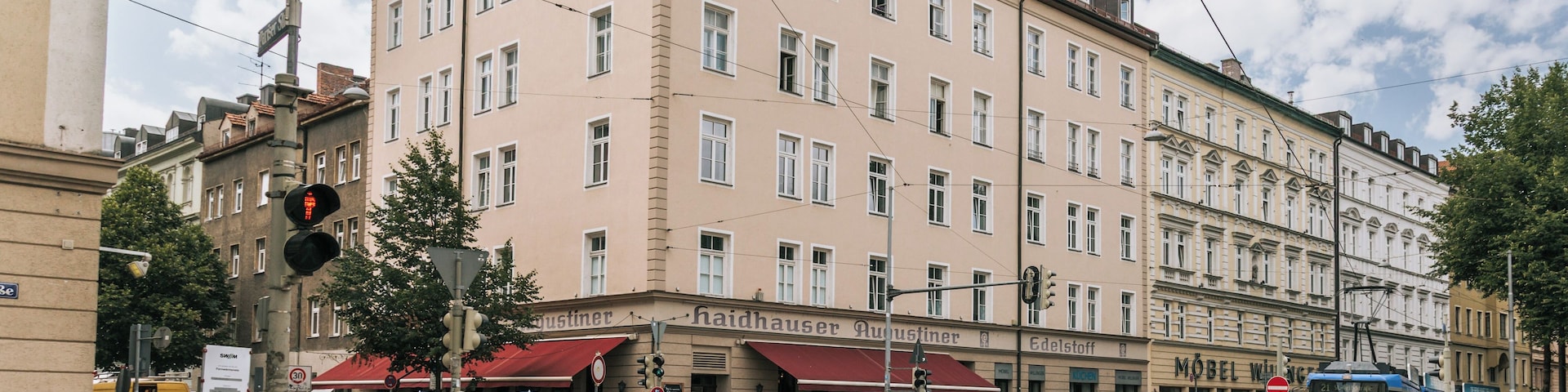A street corner with a tram, a building with a red awning, and a tree.