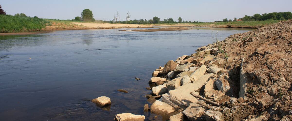 A river with rocky banks and sparse vegetation.