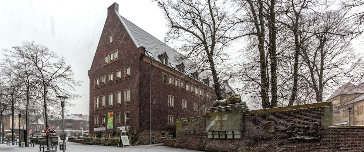 Town Hall and war memorial while snow falls, Dülmen, North Rhine-Westphalia, Germany