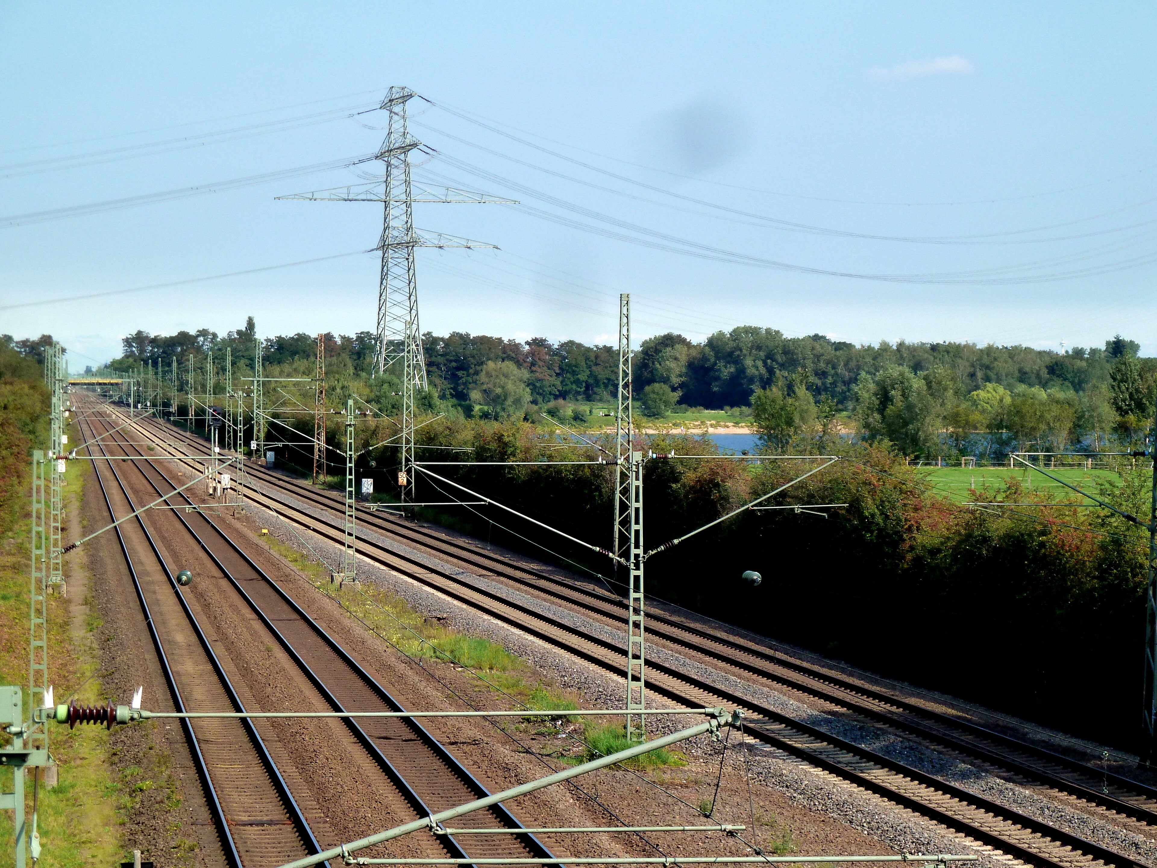 Bahnstrecke Düsseldorf–Duisburg am Angermunder See; hinten Freileitungsmast (Bl. 4142 M16, 380/220/110 kV)