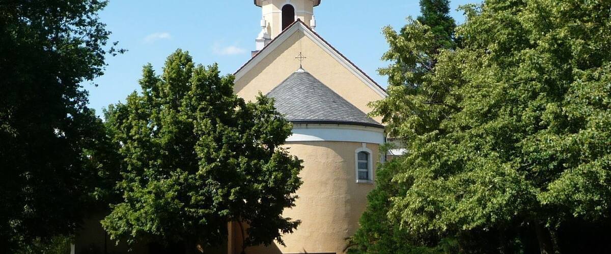 A church with a bell tower and crosses, surrounded by trees and a well-maintained lawn.