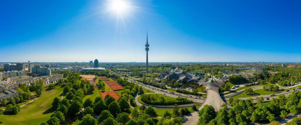 Eine Stadtansicht mit einem markanten Turm, grünen Parks und einem modernen Stadion.